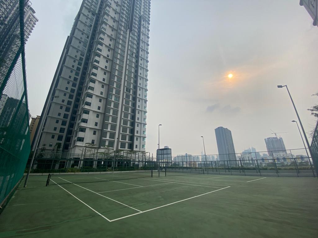Floodlit rooftop tennis court with the towers and city skyline behind